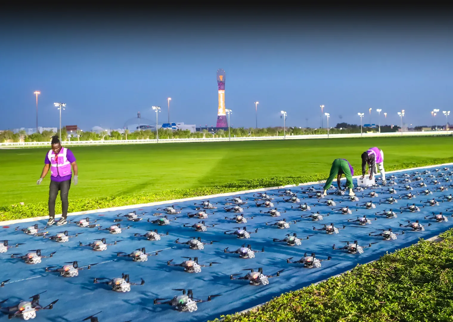 Technicians setting up drones on a large outdoor field for a show